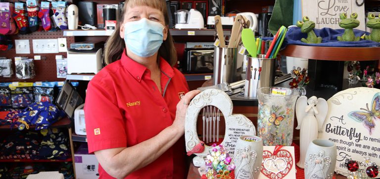 Employee standing in front of a selection of gifts