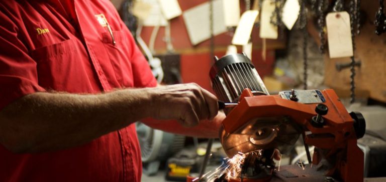 Man in red employee shirt using an industrial sharpener